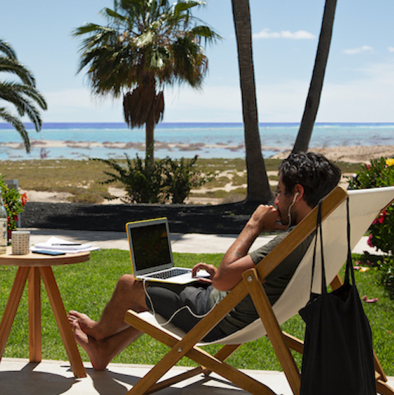 Remote worker trabajando en silla reclinable con vistas al mar