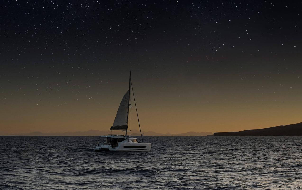 Boat sailing at sunset under a starry sky in calm waters, creating a unique experience at sea.