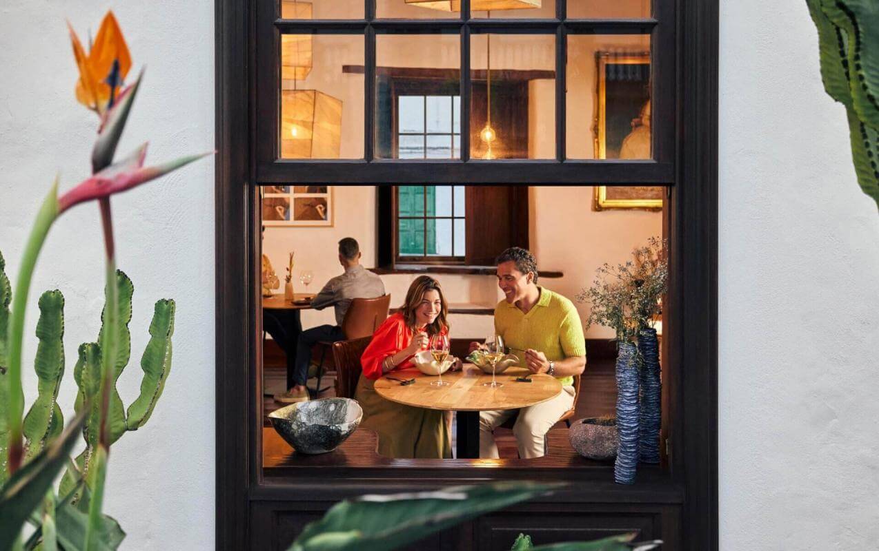 View from a window of a couple eating in a cosy restaurant with traditional décor and details from nature.