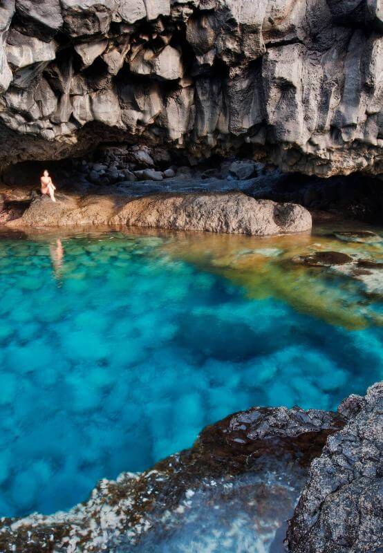 El Hierro's Charco Azul, a turquoise natural rock pool set against dark volcanic rock beneath a cliff.