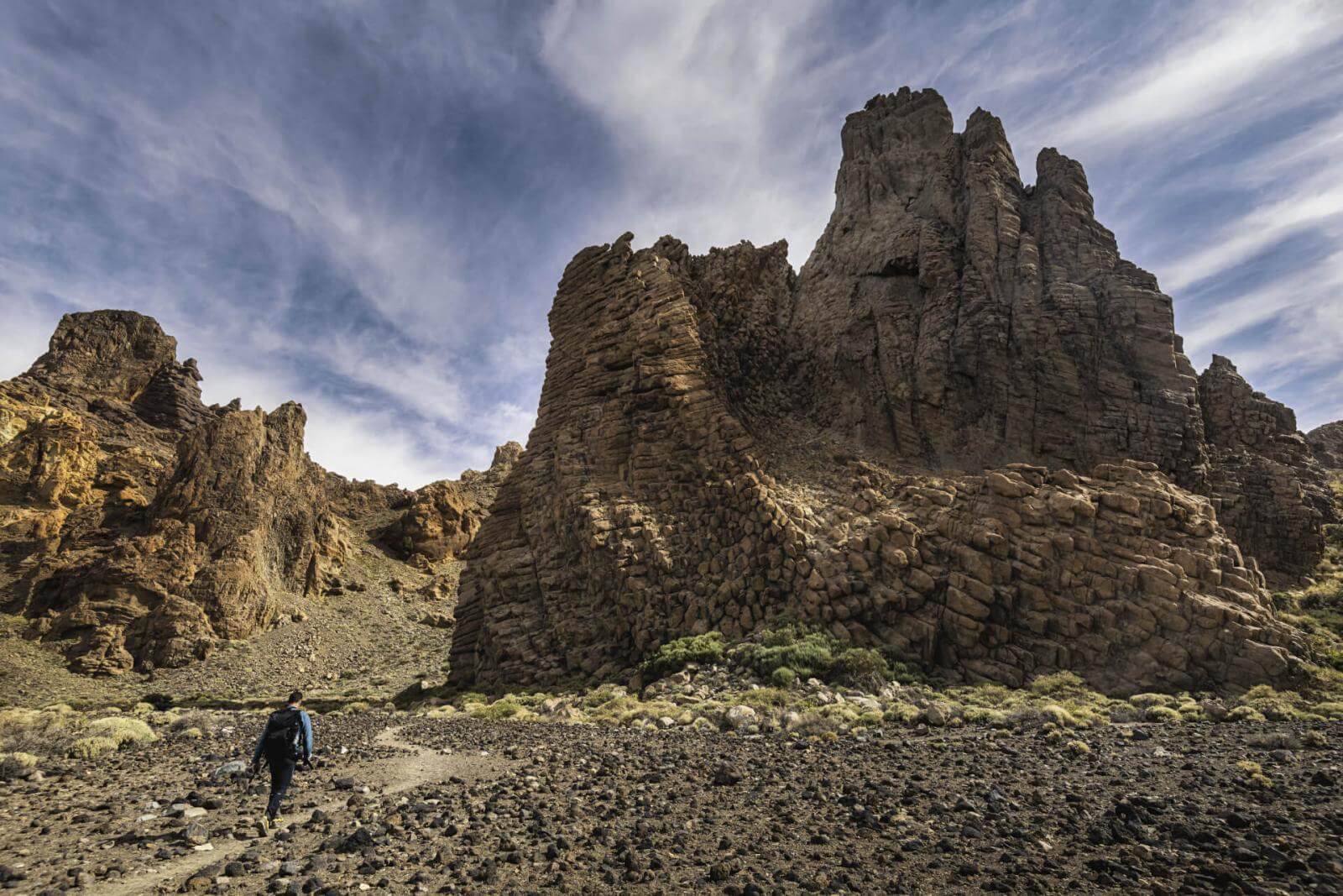 Chico con mochila haciendo senderismo entre paisajes volcánicos de las Islas Canarias