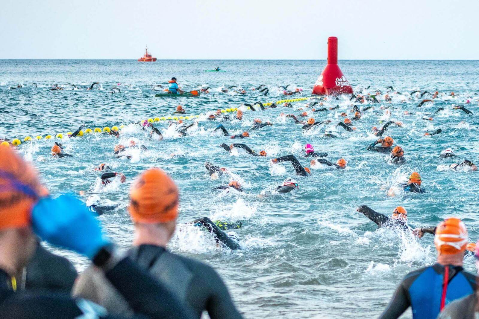 Group of swimmers competing in open water with buoys marking the course.