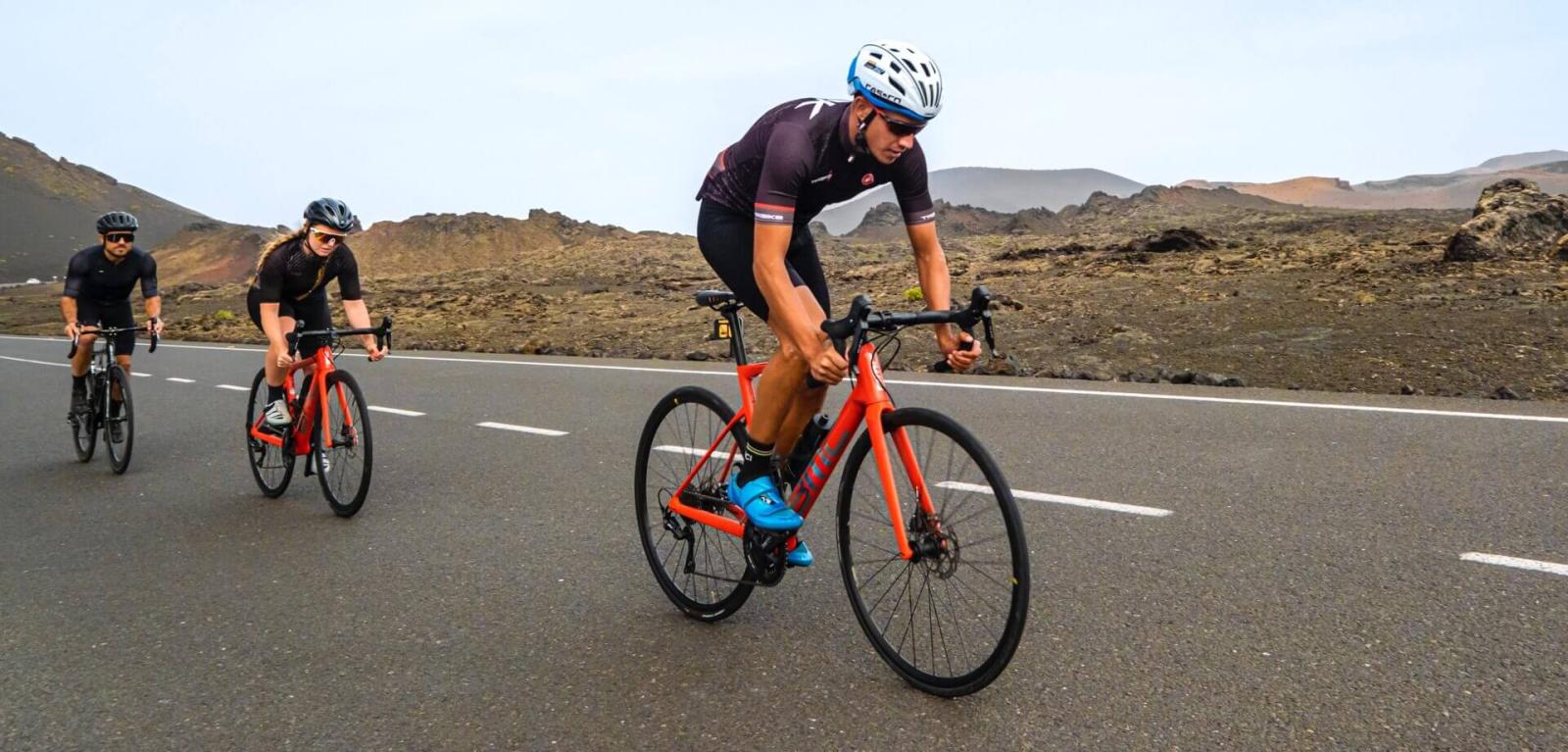 Cyclists climbing a road through a volcanic landscape.
