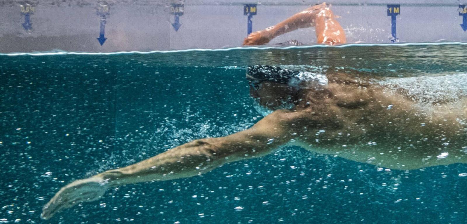 Person training in an indoor pool, partial underwater view.