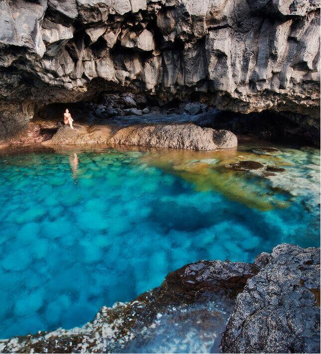 El Hierro's Charco Azul, a turquoise natural rock pool set against dark volcanic rock beneath a cliff.