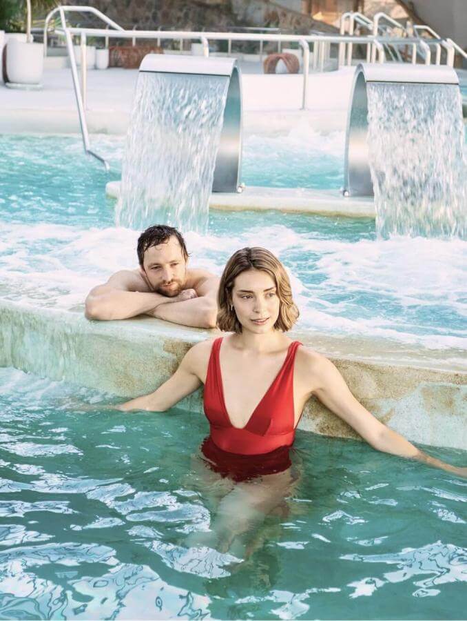 Couple enjoying a thalassotherapy pool with jets and waterfalls, in a space designed for wellness and relaxation.