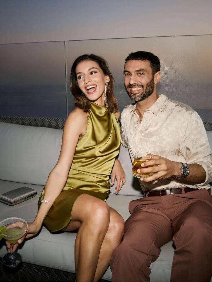 Couple enjoying cocktails on a terrace at sunset with sea views and an elegant atmosphere.