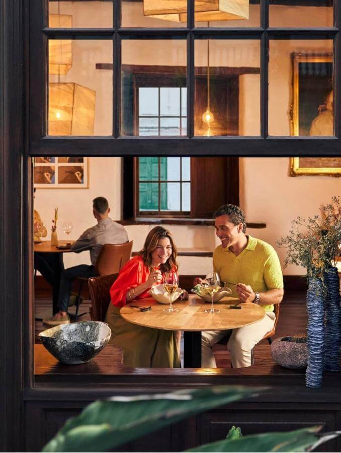 View from a window of a couple eating in a cosy restaurant with traditional décor and details from nature.